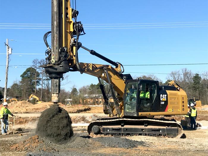 Worker standing near large drill - drilling into the ground
